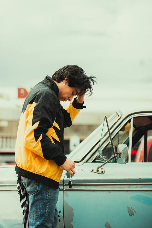 a man standing next to a car talking on a cell phone