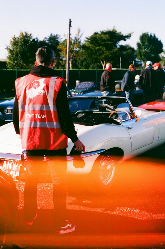 Man in red vest near vintage white convertible car